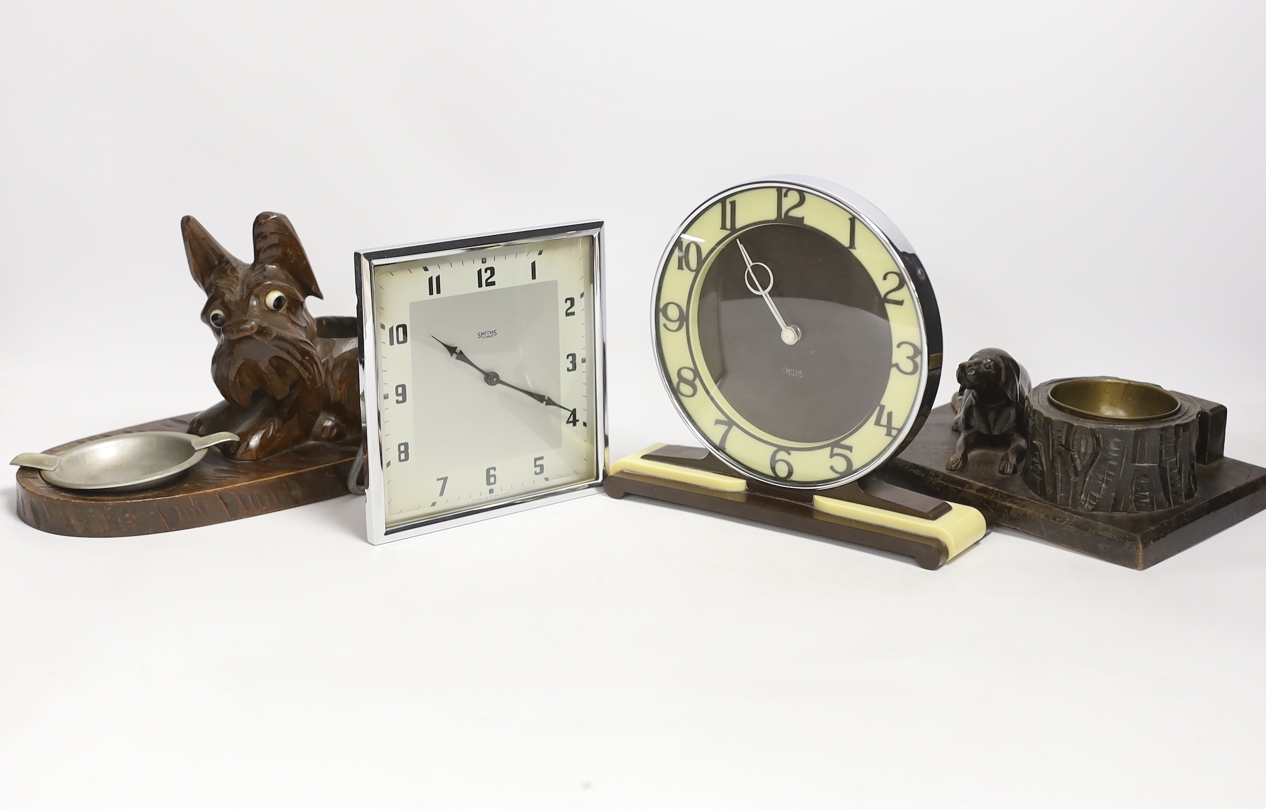 Two Art Deco clocks and two carved wood ‘dog’ ash trays, tallest 18cm